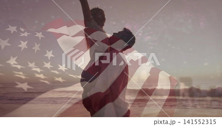 Silhouetted man lifting partner on beach at sunset, wearing casual beachwear, American flag overlay Silhouetted man lifting partner on beach at sunset, wearing casual beachwear, American flag overlay 141552315
