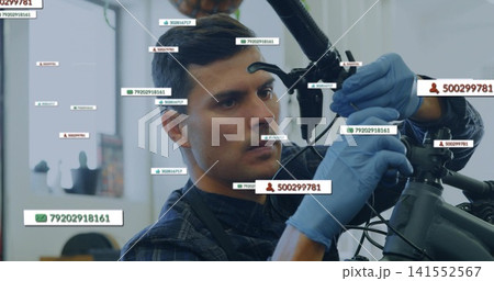 Repairing mechanic adjusting bike front brake in shop, in dark apron, blue gloves with ID labels Repairing mechanic adjusting bike front brake in shop, in dark apron, blue gloves with ID labels 141552567