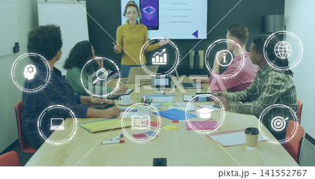 Presenting woman in mustard turtleneck gesturing toward seated team in conference room with laptops Presenting woman in mustard turtleneck gesturing toward seated team in conference room with laptops 141552767