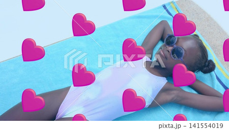 Reclining girl wearing one-piece and round sunglasses on turquoise towel by pool, heart-overlays Reclining girl wearing one-piece and round sunglasses on turquoise towel by pool, heart-overlays 141554019