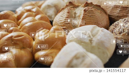 Displaying assortment of golden-brown rolls and scored loaves on bakery counter, with overlay icons Displaying assortment of golden-brown rolls and scored loaves on bakery counter, with overlay icons 141554117