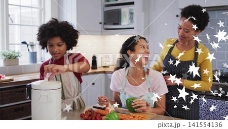 Preparing family chopping bell pepper and carrots on board at kitchen counter, wearing aprons 141554136