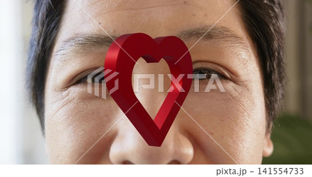Staring mid adult Asian man focusing forward in room, with glossy red 3D heart over nose 141554733