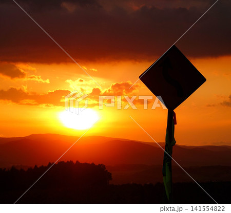穏やかな秋の夕暮れと緩やかに沈む太陽とシルエットになった標識 穏やかな秋の夕暮れと緩やかに沈む太陽とシルエットになった標識 141554822