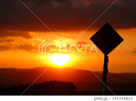 穏やかな秋の夕暮れと緩やかに沈む太陽とシルエットになった標識 141554823