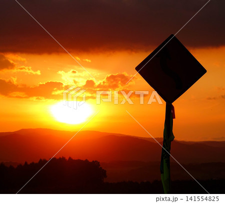 穏やかな秋の夕暮れと緩やかに沈む太陽とシルエットになった標識 穏やかな秋の夕暮れと緩やかに沈む太陽とシルエットになった標識 141554825