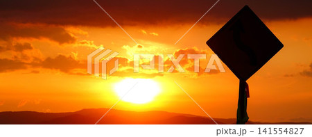 穏やかな秋の夕暮れと緩やかに沈む太陽とシルエットになった標識 穏やかな秋の夕暮れと緩やかに沈む太陽とシルエットになった標識 141554827