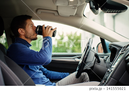Man drinking coffee in car Man drinking coffee in car 141555021