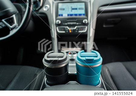 Two reusable coffee cups in car cup holders. Two reusable coffee cups in car cup holders. 141555024