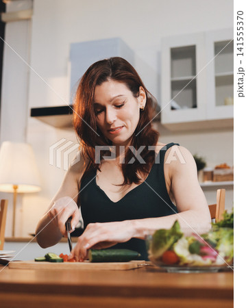 Woman preparing green smoothie in bright kitchen with fresh fruits and vegetables, healthy eating lifestyle moment in natural daylight Woman preparing green smoothie in bright kitchen with fresh fruits and vegetables, healthy eating lifestyle moment in natural daylight 141555370