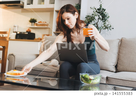 Woman preparing green smoothie in bright kitchen with fresh fruits and vegetables, healthy eating lifestyle moment in natural daylight 141555383