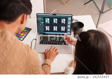 Asian photo editors reviewing photo shoot selects on laptop in studio Asian photo editors reviewing photo shoot selects on laptop in studio 141555437