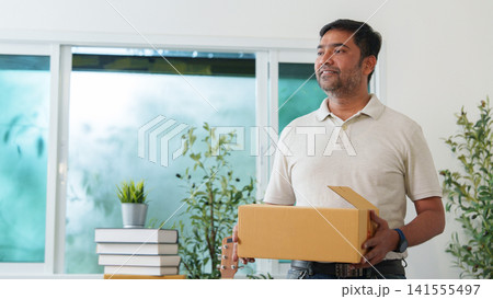 South Asian man holding cardboard package in modern home for delivery concept South Asian man holding cardboard package in modern home for delivery concept 141555497