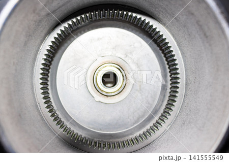 Close-up of an electric bicycle geared hub motor casing with a focus on the internal ring gear, metallic teeth, and visible traces of industrial lubricant for smooth operation Close-up of an electric bicycle geared hub motor casing with a focus on the internal ring gear, metallic teeth, and visible traces of industrial lubricant for smooth operation 141555549
