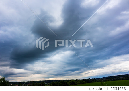 Dissipating shelf cloud formation spreads across a dramatic stormy sky, creating an ominous and powerful weather display over a green landscape at dusk during a turbulent summer day Dissipating shelf cloud formation spreads across a dramatic stormy sky, creating an ominous and powerful weather display over a green landscape at dusk during a turbulent summer day 141555628