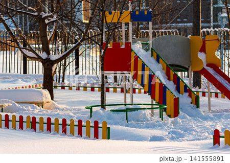 Vibrant, colorful playground equipment stands dusted with fresh white snow under bright winter sunlight, a quiet scene of frozen fun Vibrant, colorful playground equipment stands dusted with fresh white snow under bright winter sunlight, a quiet scene of frozen fun 141555891