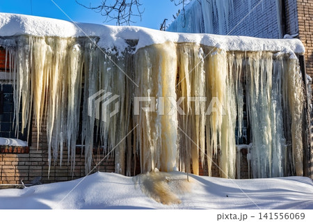 Majestic, powerful icicle formations cloak a building facade, an extraordinary urban winter sight. Bathed in cold morning light, a stunning frozen spectacle emerges. Russia, January 2026 Majestic, powerful icicle formations cloak a building facade, an extraordinary urban winter sight. Bathed in cold morning light, a stunning frozen spectacle emerges. Russia, January 2026 141556069
