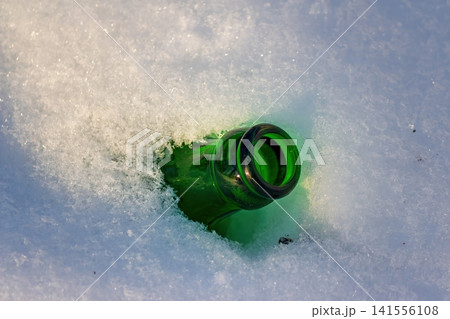 A solitary green bottle, discarded in soft, powdery snow, captures a moment of human indifference toward nature?s quiet winter landscape A solitary green bottle, discarded in soft, powdery snow, captures a moment of human indifference toward nature?s quiet winter landscape 141556108