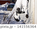 Snow-covered truck cabin hibernates under thick winter white blanket. Sun casts long shadows across the dormant vehicle, awaiting spring's thaw 141556364