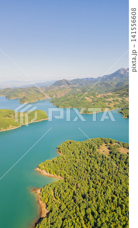 Vertical aerial view of scenic turquoise lake surrounded by wooded hills and mountains at Plastiras Dam region in Karditsa Greece for nature travel wallpaper 141556608