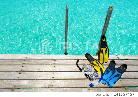Snorkeling gear on wooden deck above crystal clear tropical lagoon Snorkeling gear on wooden deck above crystal clear tropical lagoon 141557457