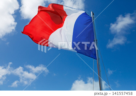 French flag waving against blue sky with white clouds French flag waving against blue sky with white clouds 141557458