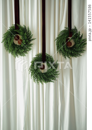 Hanging Christmas Wreaths on White Draped Backdrop 141557586