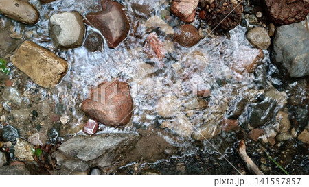 Clear stream water flowing over smooth stones and pebbles in natural setting Clear stream water flowing over smooth stones and pebbles in natural setting 141557857