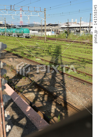 貨物列車がいる駅の風景;鉄塔の影が線路に伸びる 貨物列車がいる駅の風景;鉄塔の影が線路に伸びる 141558345