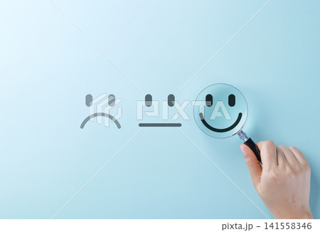 Customer feedback and Satisfaction survey concept. A hand holding magnifying glass focus on a smile face amidst different emotions, customer review, satisfaction feedback, and service improvement. Customer feedback and Satisfaction survey concept. A hand holding magnifying glass focus on a smile face amidst different emotions, customer review, satisfaction feedback, and service improvement. 141558346
