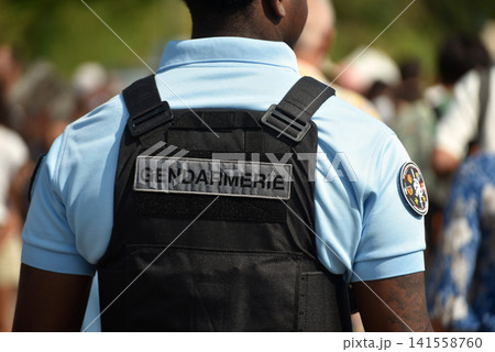 Rear view of a French Gendarmerie officer wearing a tactical vest with the official Gendarmerie insignia during a public event in France. Rear view of a French Gendarmerie officer wearing a tactical vest with the official Gendarmerie insignia during a public event in France. 141558760