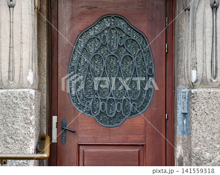 Ornate wooden entrance door with decorative wrought iron grille 141559318