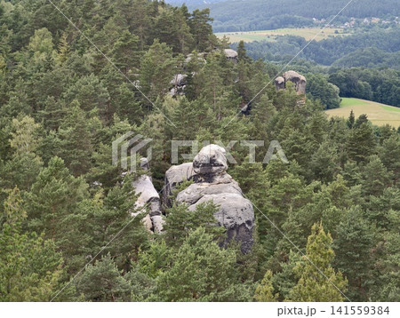 Granite rock formations rising from dense evergreen forest on hilly landscape Granite rock formations rising from dense evergreen forest on hilly landscape 141559384