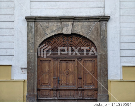 Aged wooden double door with carved arch and stone surround Aged wooden double door with carved arch and stone surround 141559594