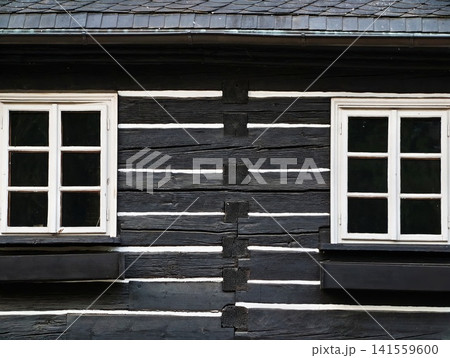 Black timber cottage facade with white framed windows and shutters Black timber cottage facade with white framed windows and shutters 141559600