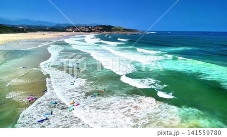 Spectacular Beach Waves with Surfers Enjoying Their Time Under Clear Blue Skies Above Spectacular Beach Waves with Surfers Enjoying Their Time Under Clear Blue Skies Above 141559780