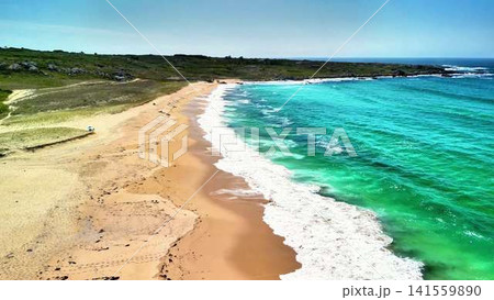 Breathtaking Aerial View of a Pristine Beach Next to Turquoise Waves and Clear Skies 141559890