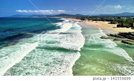 Experience the serene coastal view featuring gentle waves crashing against a sandy beach Experience the serene coastal view featuring gentle waves crashing against a sandy beach 141559899