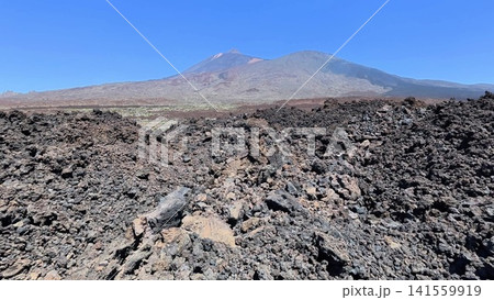 A stunning lava field with a majestic volcanic mountain range as a backdrop, incredible sight A stunning lava field with a majestic volcanic mountain range as a backdrop, incredible sight 141559919