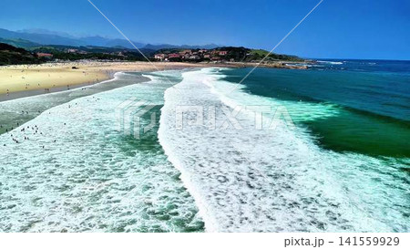 Experience the breathtaking beauty of beach waves crashing gently under a clear blue sky Experience the breathtaking beauty of beach waves crashing gently under a clear blue sky 141559929