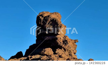 A Majestic Rock Formation Standing Tall Against a Clear Blue Sky Filled With Serenity A Majestic Rock Formation Standing Tall Against a Clear Blue Sky Filled With Serenity 141560228