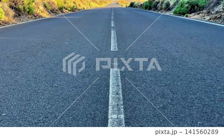 A scenic empty road with a breathtaking mountain view at dawn, ideal for adventure A scenic empty road with a breathtaking mountain view at dawn, ideal for adventure 141560289