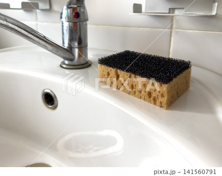 Kitchen sink with chrome faucet and sponge on white countertop Kitchen sink with chrome faucet and sponge on white countertop 141560791