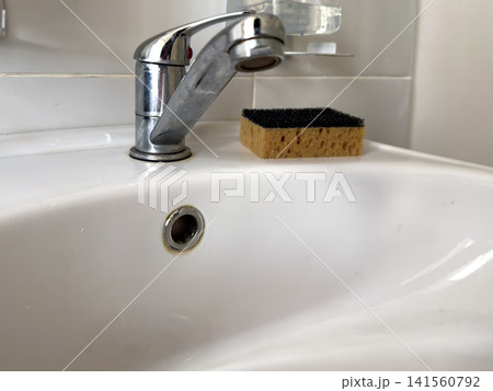 Kitchen sink with chrome faucet and sponge on white countertop Kitchen sink with chrome faucet and sponge on white countertop 141560792