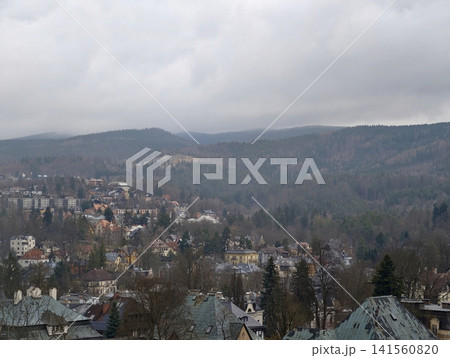 Serene natural scenery. Undisturbed forested slopes surrounding secluded townscape veiled in morning fog 141560820