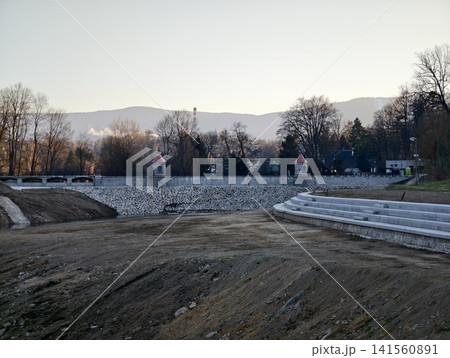 An aged water reservoir with nearby hills. Drained reservoir showcasing steps and eroded banks An aged water reservoir with nearby hills. Drained reservoir showcasing steps and eroded banks 141560891