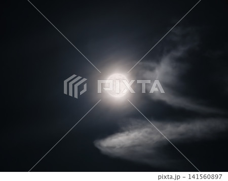 Luminous moon surrounded by floating clouds casts gentle silver light over tranquil night atmosphere 141560897