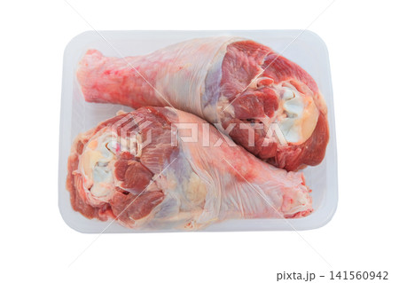 Raw turkey drumsticks in a white container isolated on a white background. Dietary meat for cooking. Cooking food at home. Top view. Raw turkey drumsticks in a white container isolated on a white background. Dietary meat for cooking. Cooking food at home. Top view. 141560942