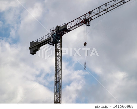 Crane silhouettes rise. Industrial skyline showing steel lattice crane amidst clouds and urban growth Crane silhouettes rise. Industrial skyline showing steel lattice crane amidst clouds and urban growth 141560969