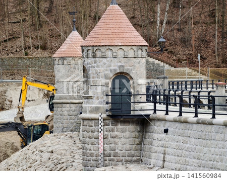 Excavation and masonry work at spillway. Industrial machinery alongside historic stone architecture Excavation and masonry work at spillway. Industrial machinery alongside historic stone architecture 141560984